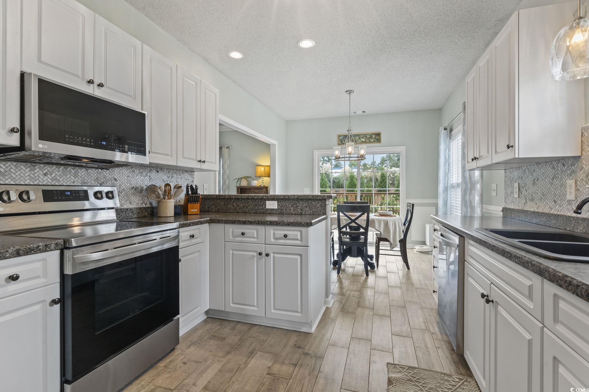212 Duchess Court Myrtle Beach, SC 29588 - Photo 4 of 40 Kitchen with decorative backsplash, appliances with stainless steel finishes, white cabinetry, decorative light fixtures, and a textured ceiling