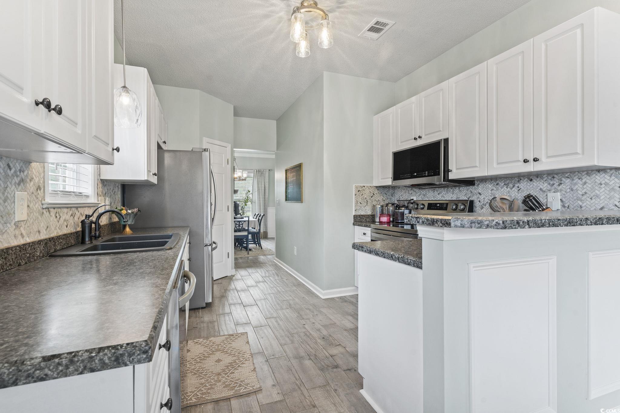 212 Duchess Court Myrtle Beach, SC 29588 - Photo 9 of 40 Kitchen with tasteful backsplash, white cabinets, dark countertops, healthy amount of natural light, and a textured ceiling