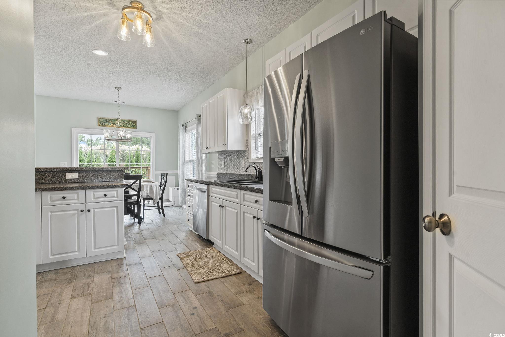 212 Duchess Court Myrtle Beach, SC 29588 - Photo 10 of 40 Kitchen with stainless steel appliances, white cabinets, dark stone counters, a textured ceiling, and pendant lighting