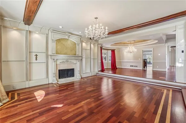 a view of an empty room with wooden floor fireplace and a window