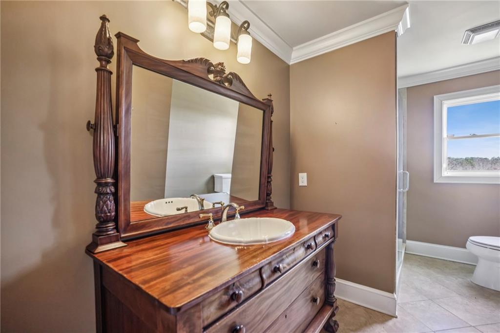 6525 Garrett Road Buford, GA 30518 - Photo 56 of 98 a bathroom with a sink a mirror and a toilet