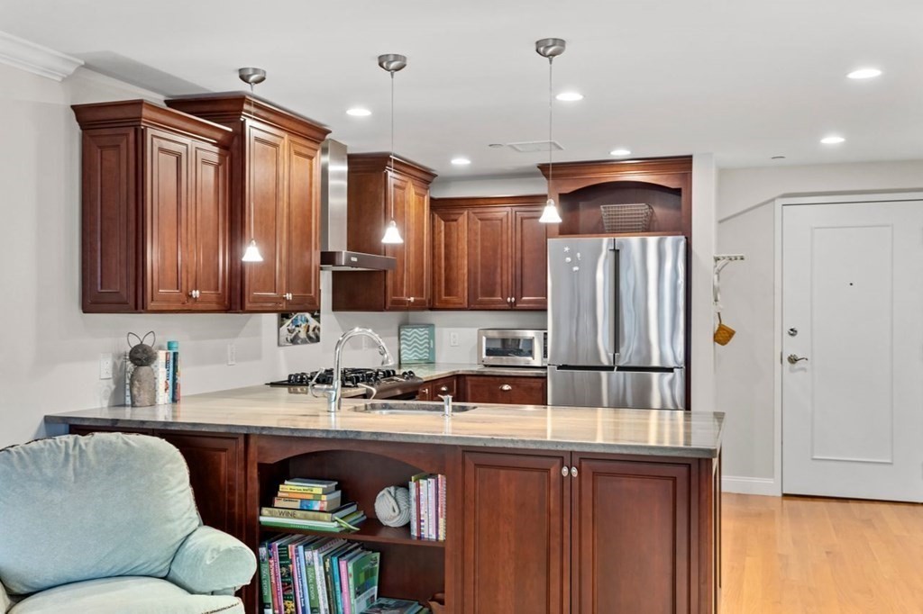 91 Front Street, Unit 104 Scituate, MA 02066 - Photo 15 of 26 a kitchen with stainless steel appliances granite countertop a refrigerator a sink dishwasher a stove with wooden cabinets and floor