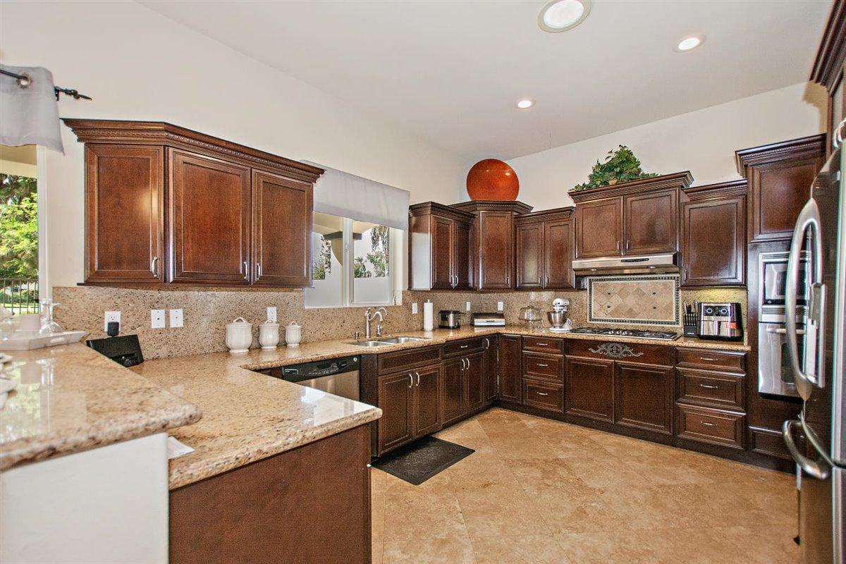 82553 Doolittle Drive Indio, CA 92201 - Photo 12 of 47 a kitchen with stainless steel appliances granite countertop a sink and dishwasher a stove top oven with wooden floor
