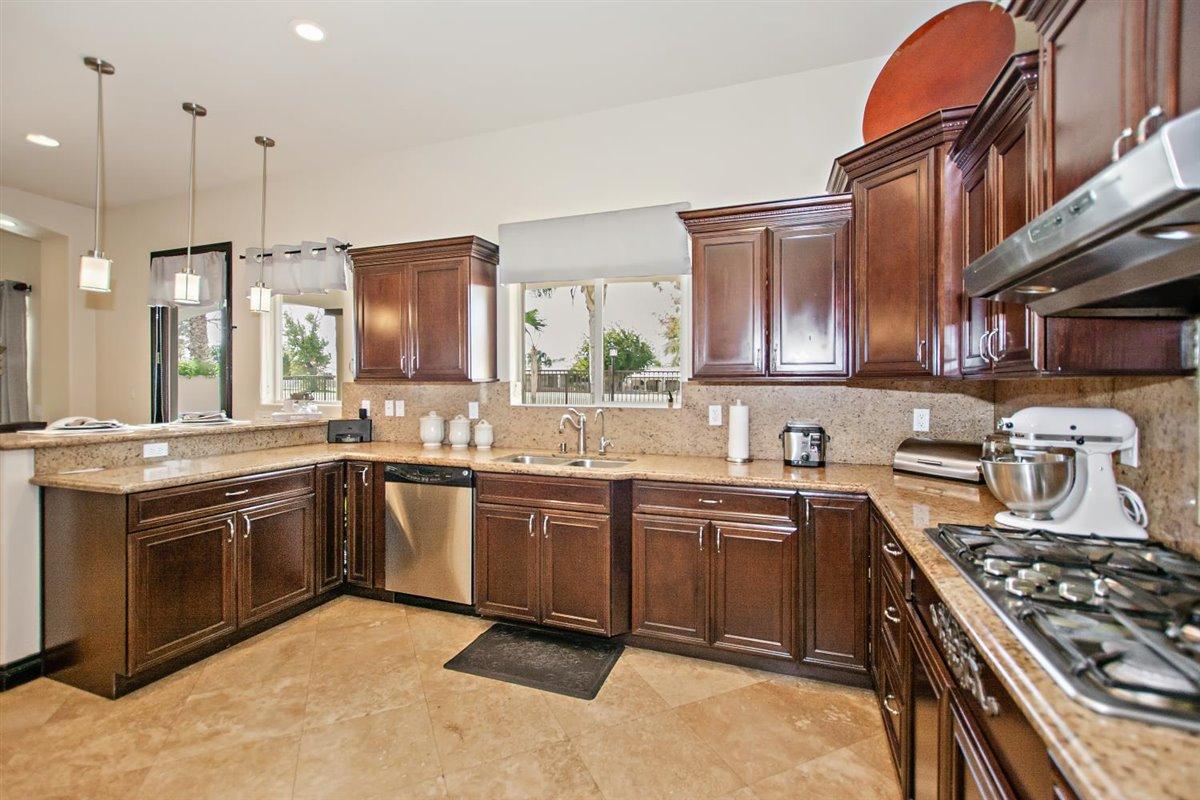 82553 Doolittle Drive Indio, CA 92201 - Photo 13 of 47 a kitchen with stainless steel appliances granite countertop a stove a sink dishwasher and a refrigerator