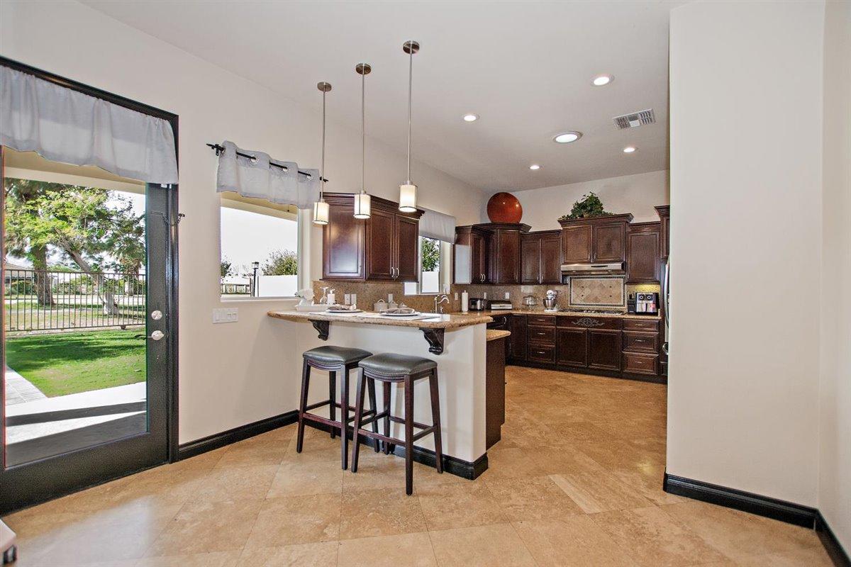 82553 Doolittle Drive Indio, CA 92201 - Photo 15 of 47 a kitchen with kitchen island granite countertop wooden cabinets and white appliances