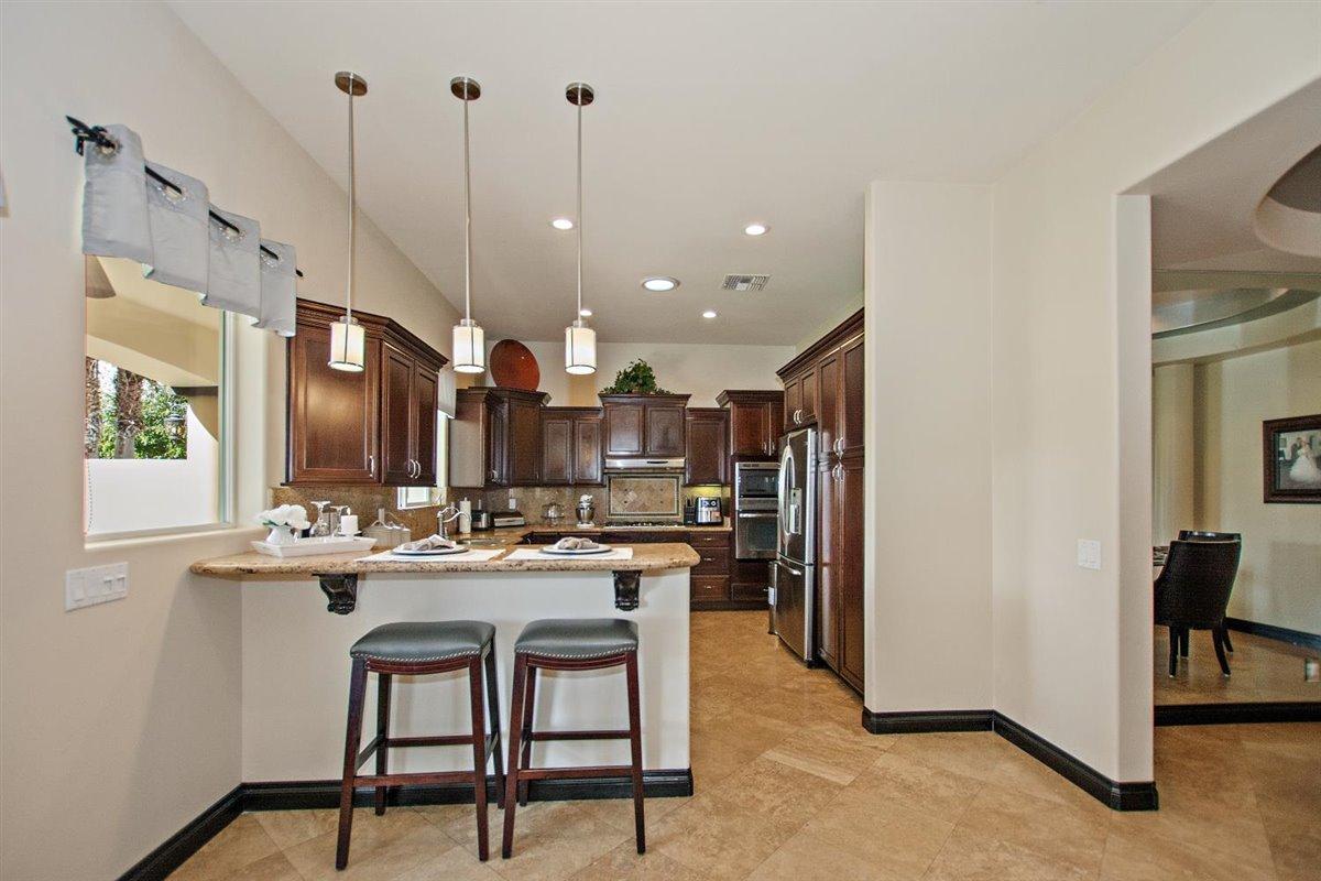82553 Doolittle Drive Indio, CA 92201 - Photo 16 of 47 a kitchen with stainless steel appliances kitchen island a chandelier and refrigerator