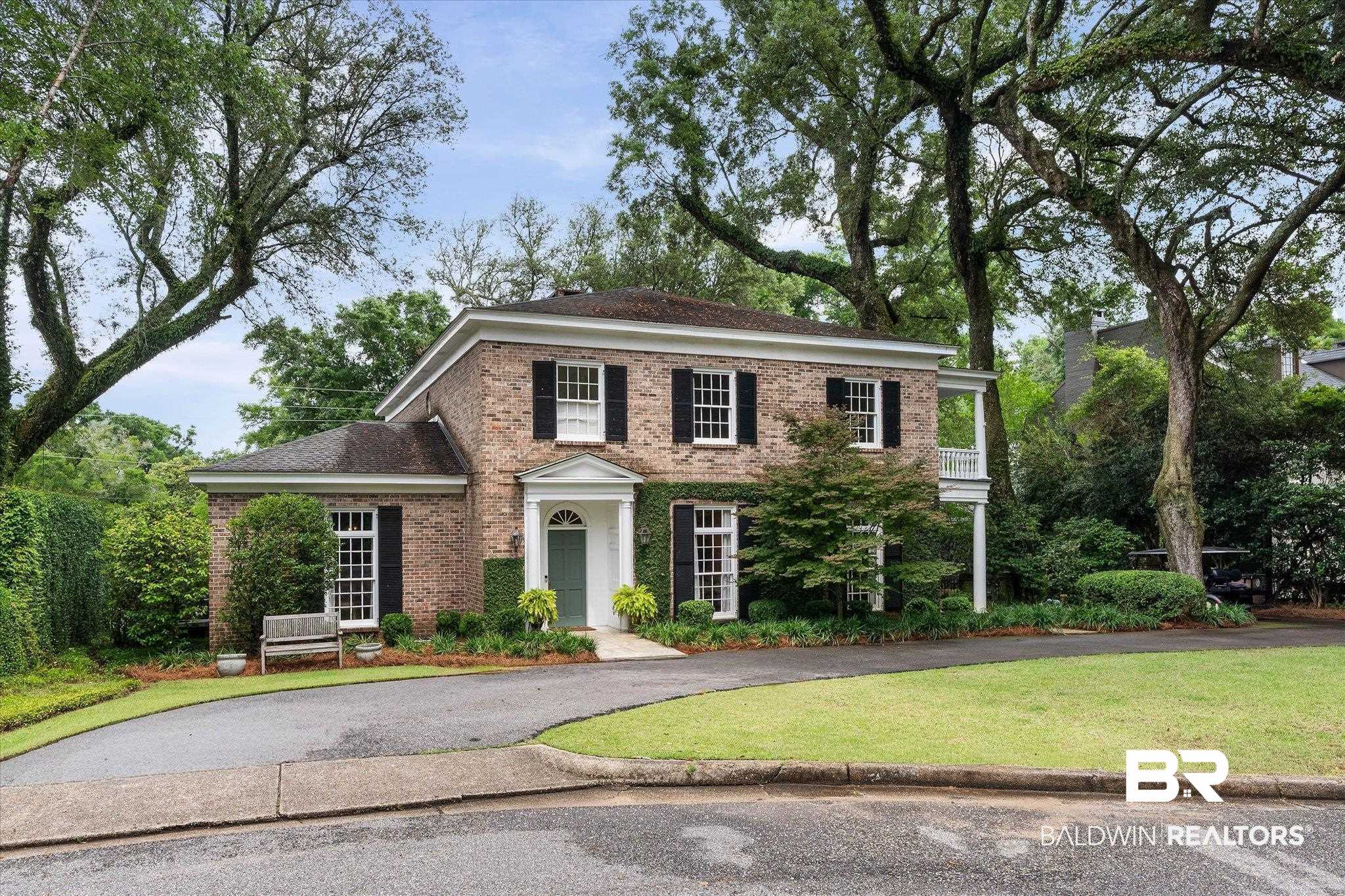 3908 Yester Place Mobile, AL 36608 - Photo 3 of 45 Brick residence featuring a prominent front entrance with a portico, a second-story balcony with white columns, black louvered shutters, and a green front door