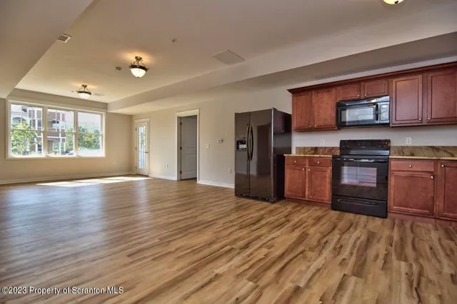 a kitchen with stainless steel appliances granite countertop a refrigerator a stove top oven a sink and dishwasher with wooden floor