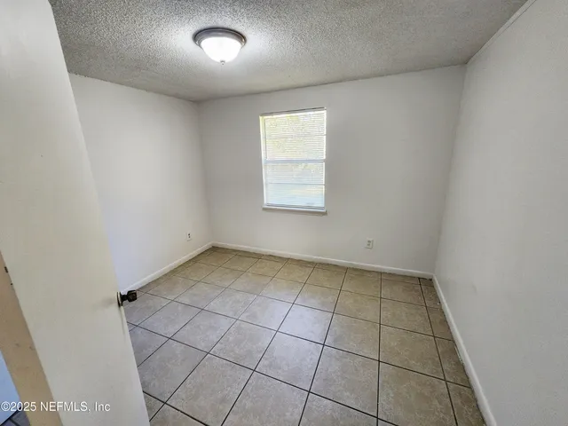 an empty room with a white cabinet and tiles