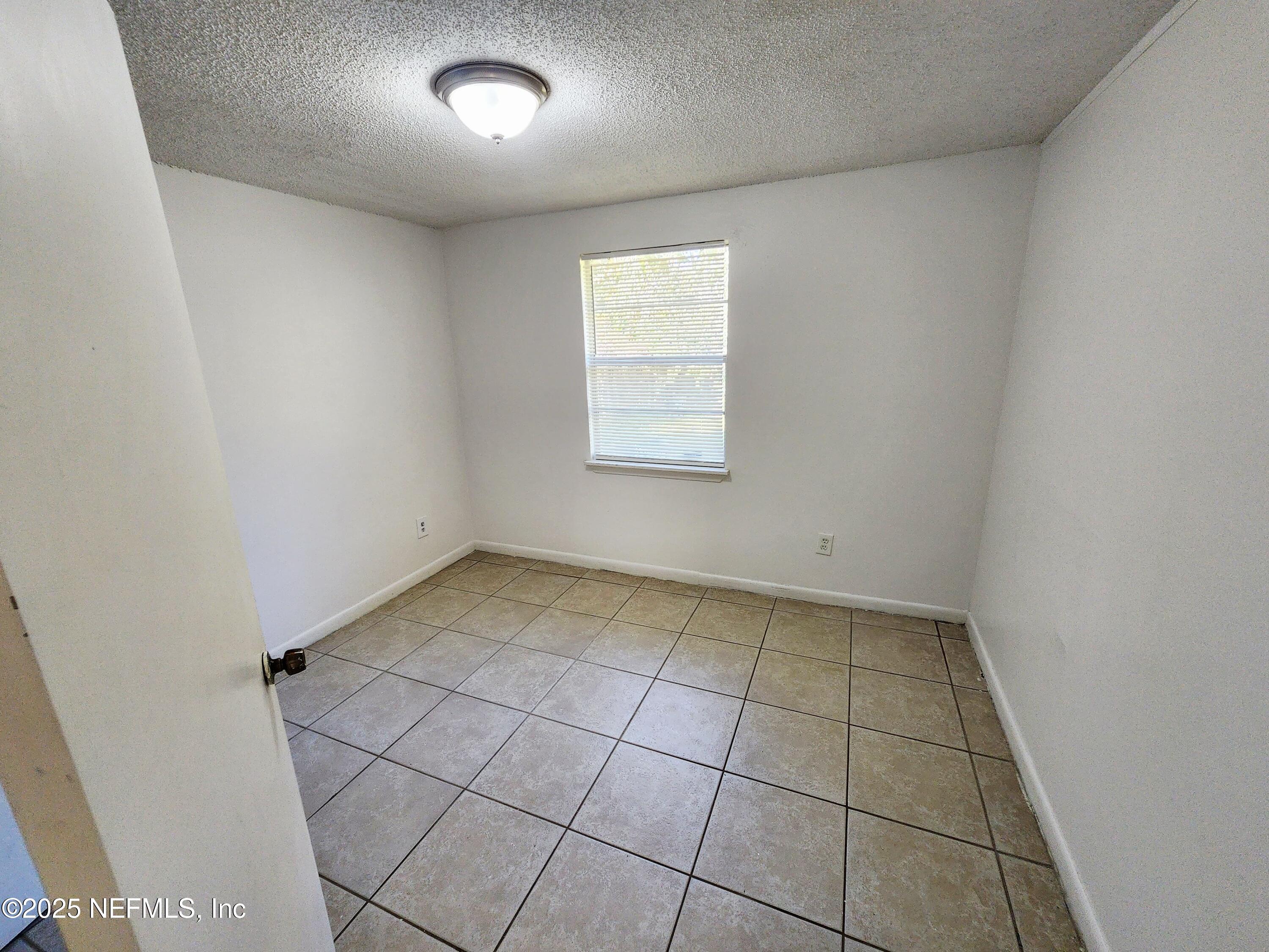 7127 Prellie Street Jacksonville, FL 32210 - Photo 9 of 16 an empty room with a white cabinet and tiles