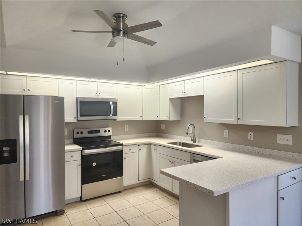a kitchen with stainless steel appliances a sink a stove a refrigerator cabinets and a window