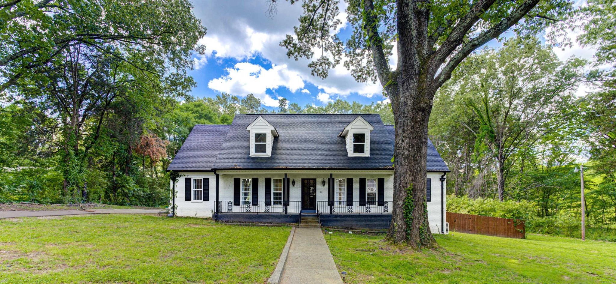 a view of a house with a yard and a large tree
