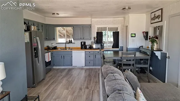a living room with stainless steel appliances granite countertop furniture a kitchen view living room and wooden floor