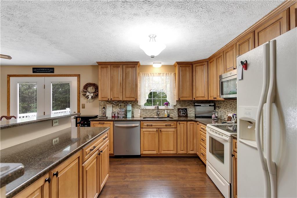 227 Brewer Road Freedom, PA 15042 - Photo 9 of 34 a kitchen with stainless steel appliances granite countertop a stove a sink dishwasher a refrigerator and white cabinets with wooden floor