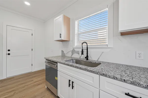a kitchen with granite countertop white cabinets and a sink