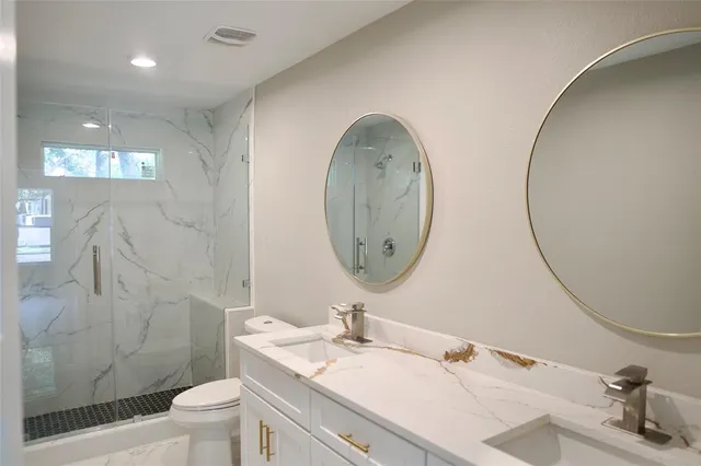 a bathroom with a granite countertop toilet a sink and a mirror