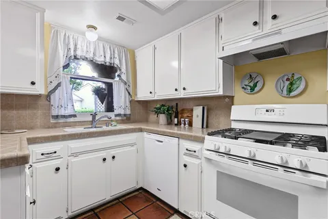 a kitchen with granite countertop white cabinets and white appliances