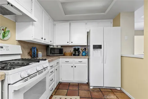 a kitchen with white cabinets and appliances
