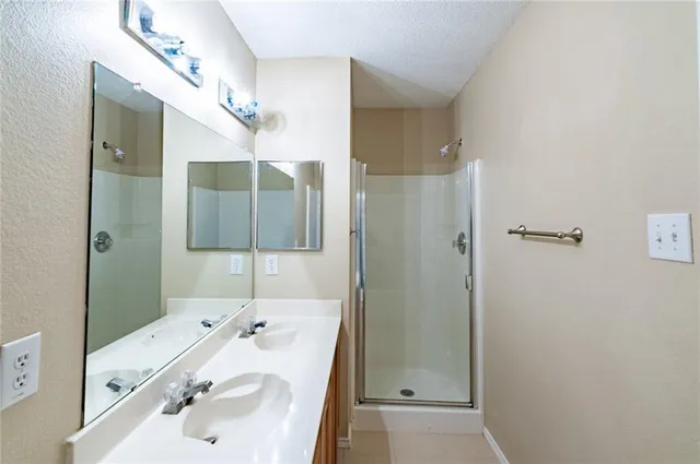 a bathroom with a sink and mirror with shower