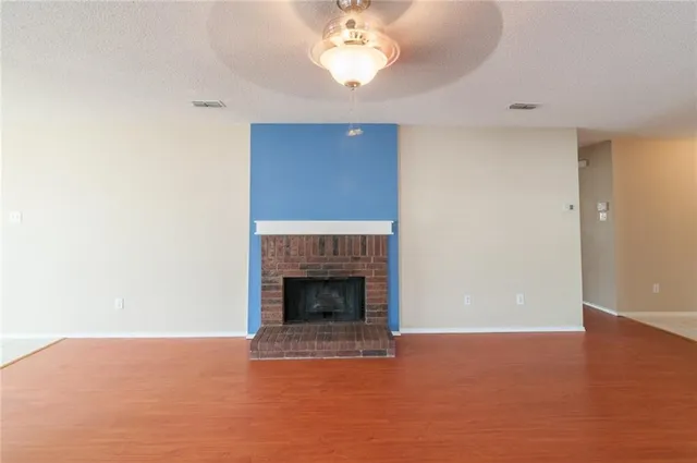 a view of an empty room with chandelier fan and fire place