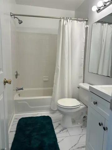 a bathroom with a sink a toilet a mirror a bathtub and shower