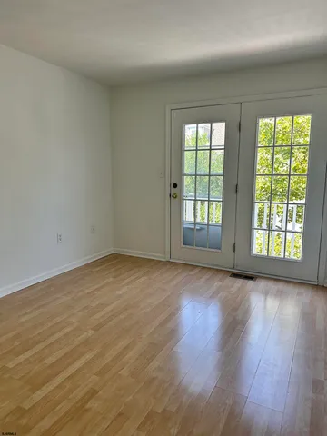 an empty room with wooden floor and windows