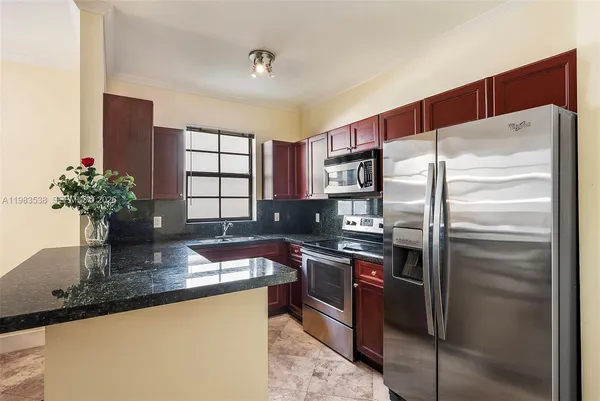 a kitchen with stainless steel appliances granite countertop a sink and a refrigerator
