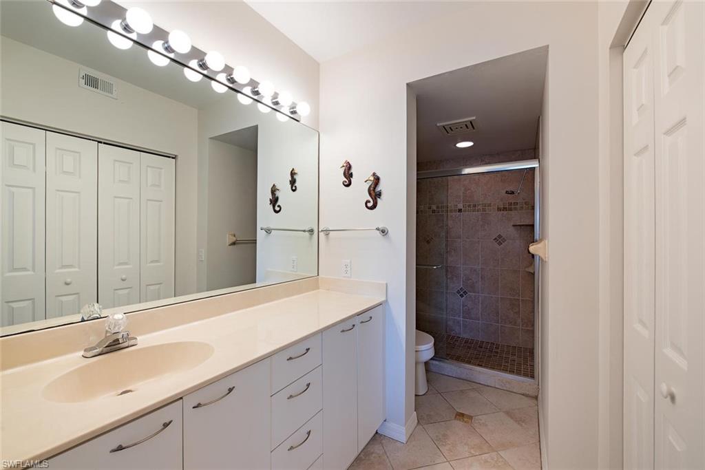 4960 Deerfield Way, Unit E103 Naples, FL 34110 - Photo 11 of 14 a spacious bathroom with a shower sink and mirror