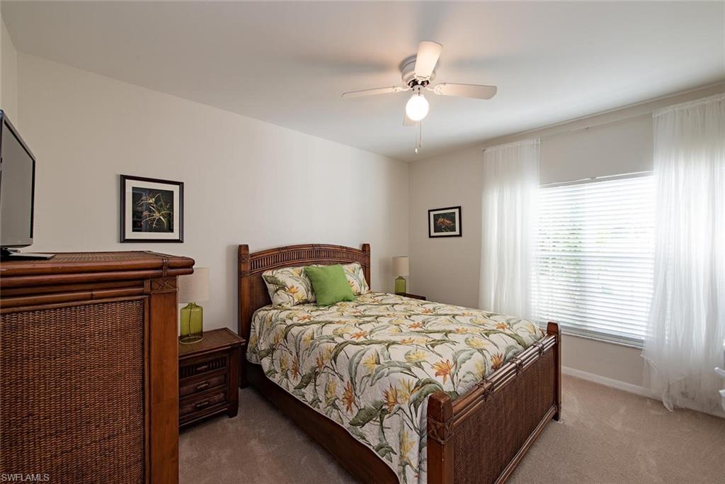 4960 Deerfield Way, Unit E103 Naples, FL 34110 - Photo 9 of 14 a bedroom with a bed and a chandelier