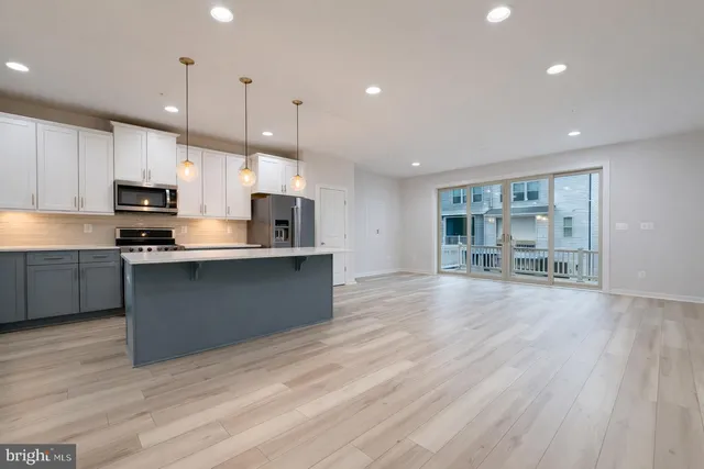 a large kitchen with stainless steel appliances granite countertop a large counter top a sink dishwasher and a stove with wooden floor