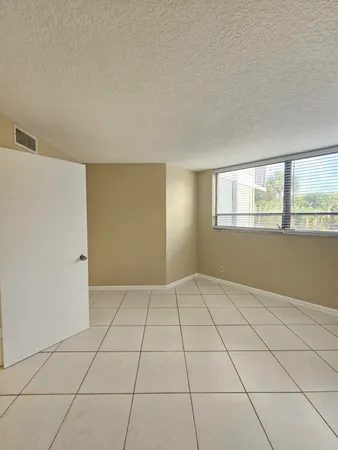 a view of an empty room with window and chandelier fan