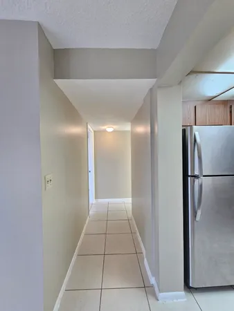 a view of a refrigerator in kitchen and an empty room