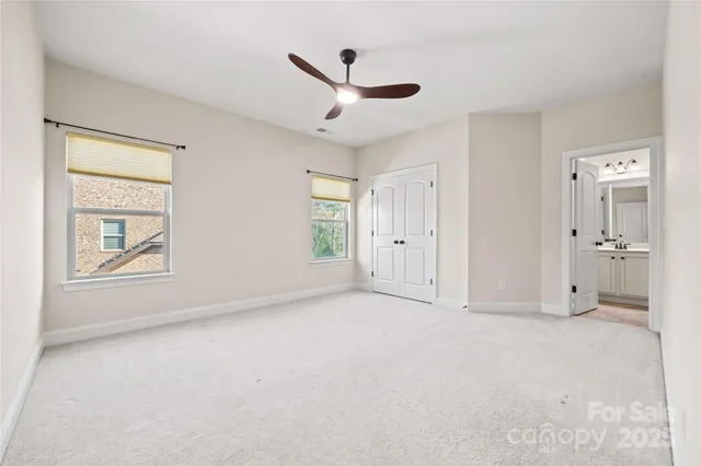 an empty room with chandelier fan and windows