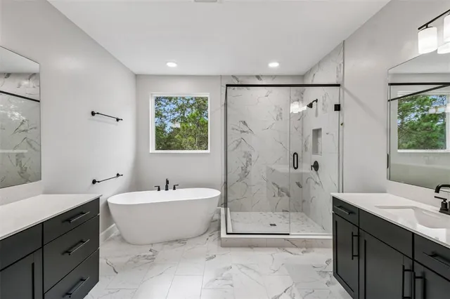 a bathroom with a tub sink mirror and a shower