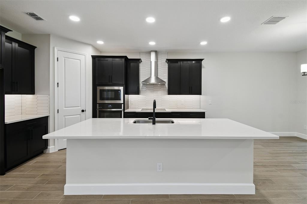 5262 Prairie Preserve Run St. Cloud, FL 34772 - Photo 4 of 40 a large white kitchen with kitchen island granite countertop a stove and a sink