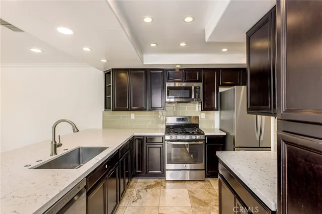 a kitchen with stainless steel appliances granite countertop a sink a stove and a refrigerator
