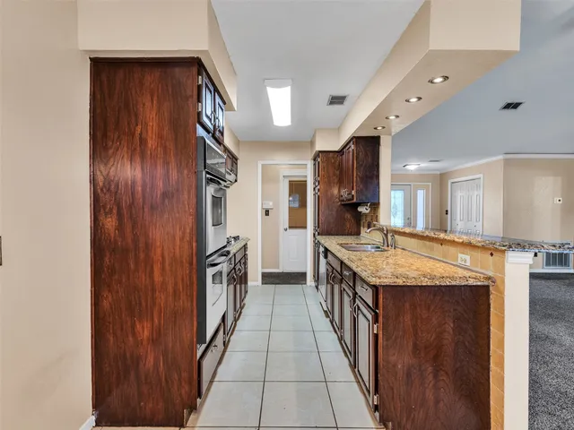 a kitchen with granite countertop a sink and a refrigerator