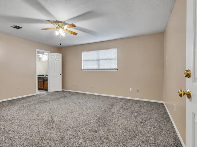 an empty room with chandelier fan and windows
