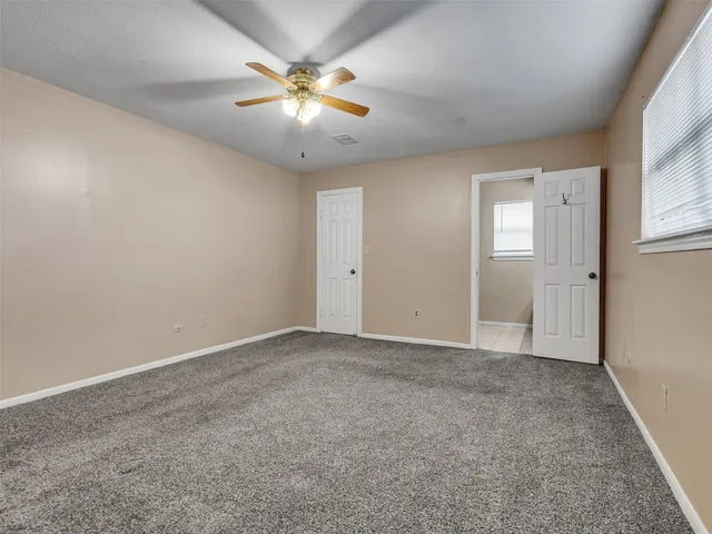 an empty room with chandelier fan and windows