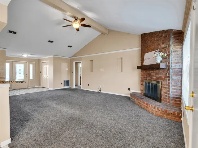 a view of a livingroom with a fireplace a ceiling fan and window