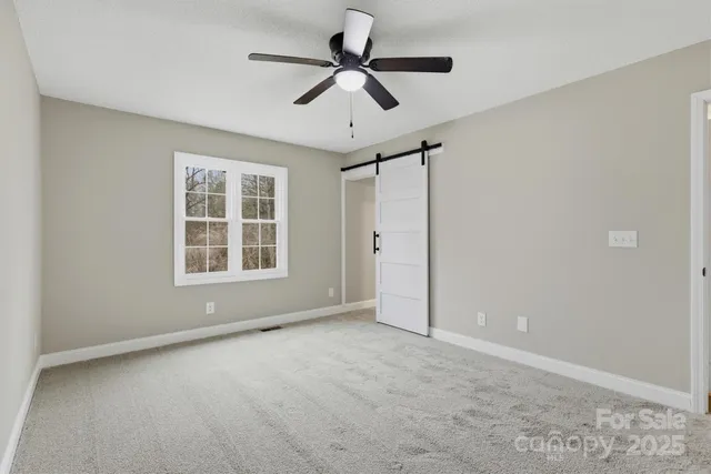 an empty room with windows and ceiling fan