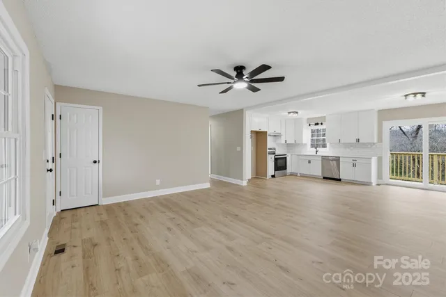 a view of a livingroom with a flat screen tv wooden floor and a ceiling fan
