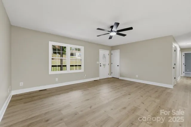 a view of an empty room with a window and wooden floor