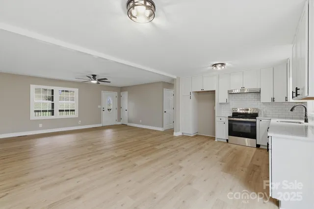 a large kitchen with a stove a sink dishwasher and a refrigerator with wooden floor