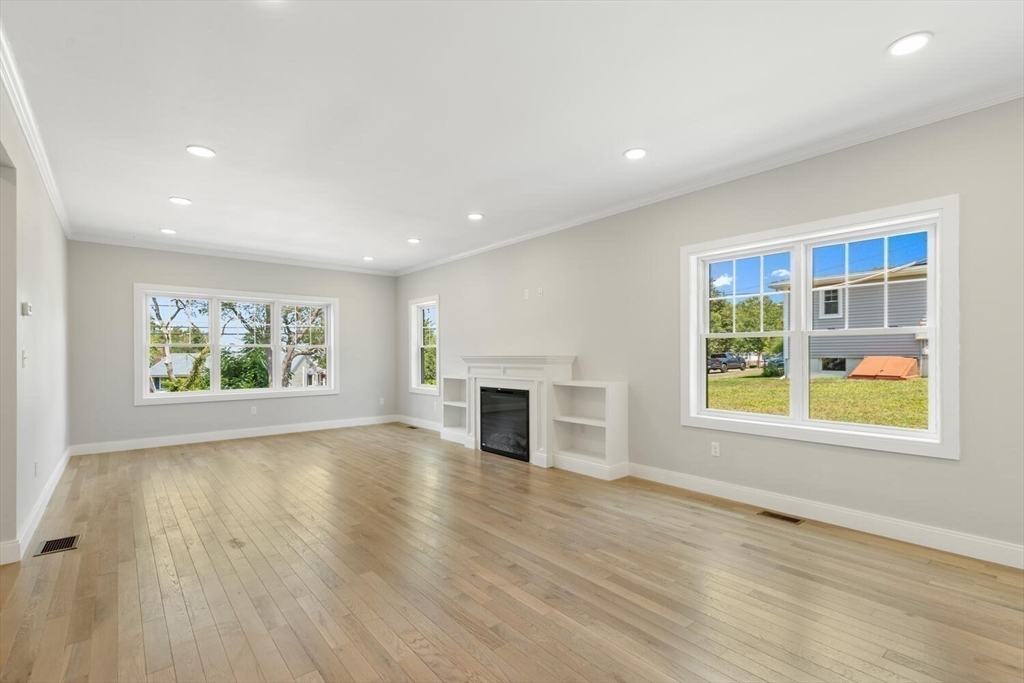 28 Riverview Road, Unit A Gloucester, MA 01930 - Photo 12 of 36 an empty room with windows fireplace and wooden floor