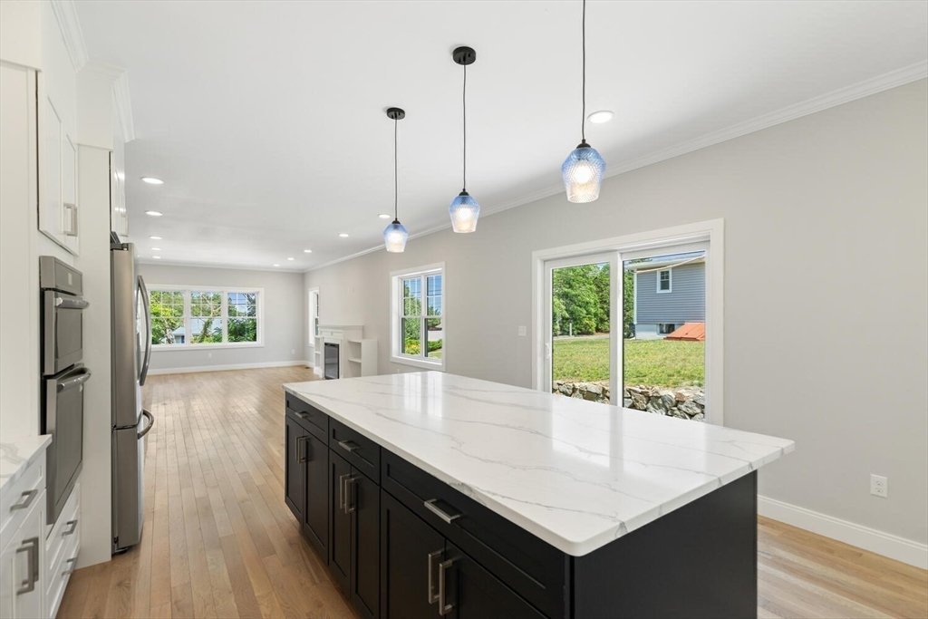 28 Riverview Road, Unit A Gloucester, MA 01930 - Photo 9 of 36 a kitchen with kitchen island a center island wooden floor and a chandelier
