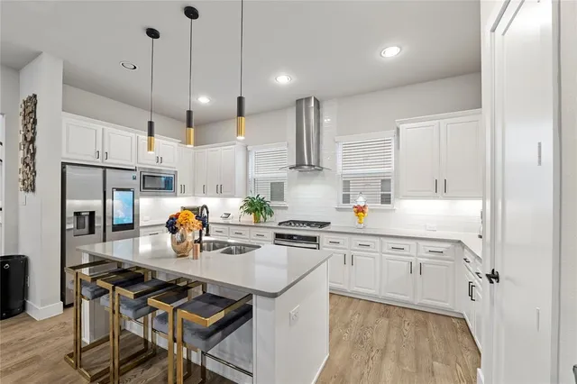 a kitchen with a sink a stove a refrigerator and white cabinets with wooden floor