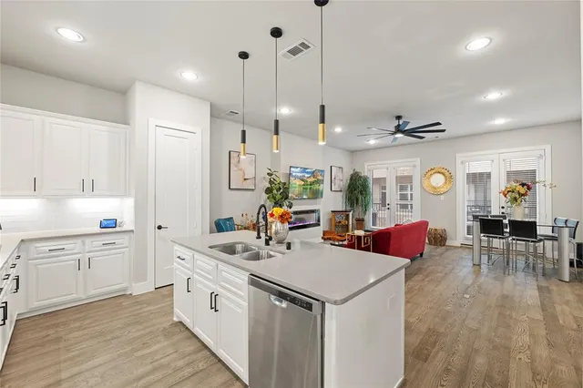 a kitchen with stainless steel appliances granite countertop a sink dishwasher and white cabinets with wooden floor