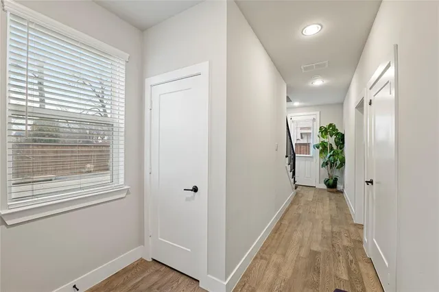 a view of a hallway with wooden floor and a bathroom