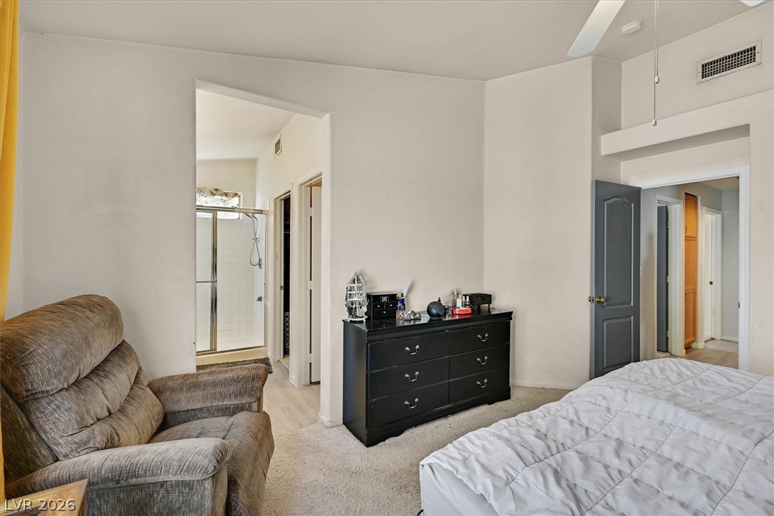 8830 Haviland Road Las Vegas, NV 89123 - Photo 17 of 43 An open doorway connects the carpeted bedroom with vaulted ceilings to an ensuite bathroom.